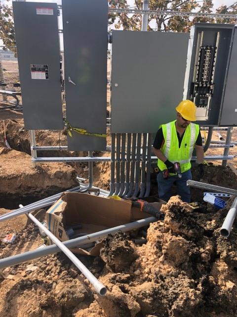 commercial electrician standing in trench installing electrical lines